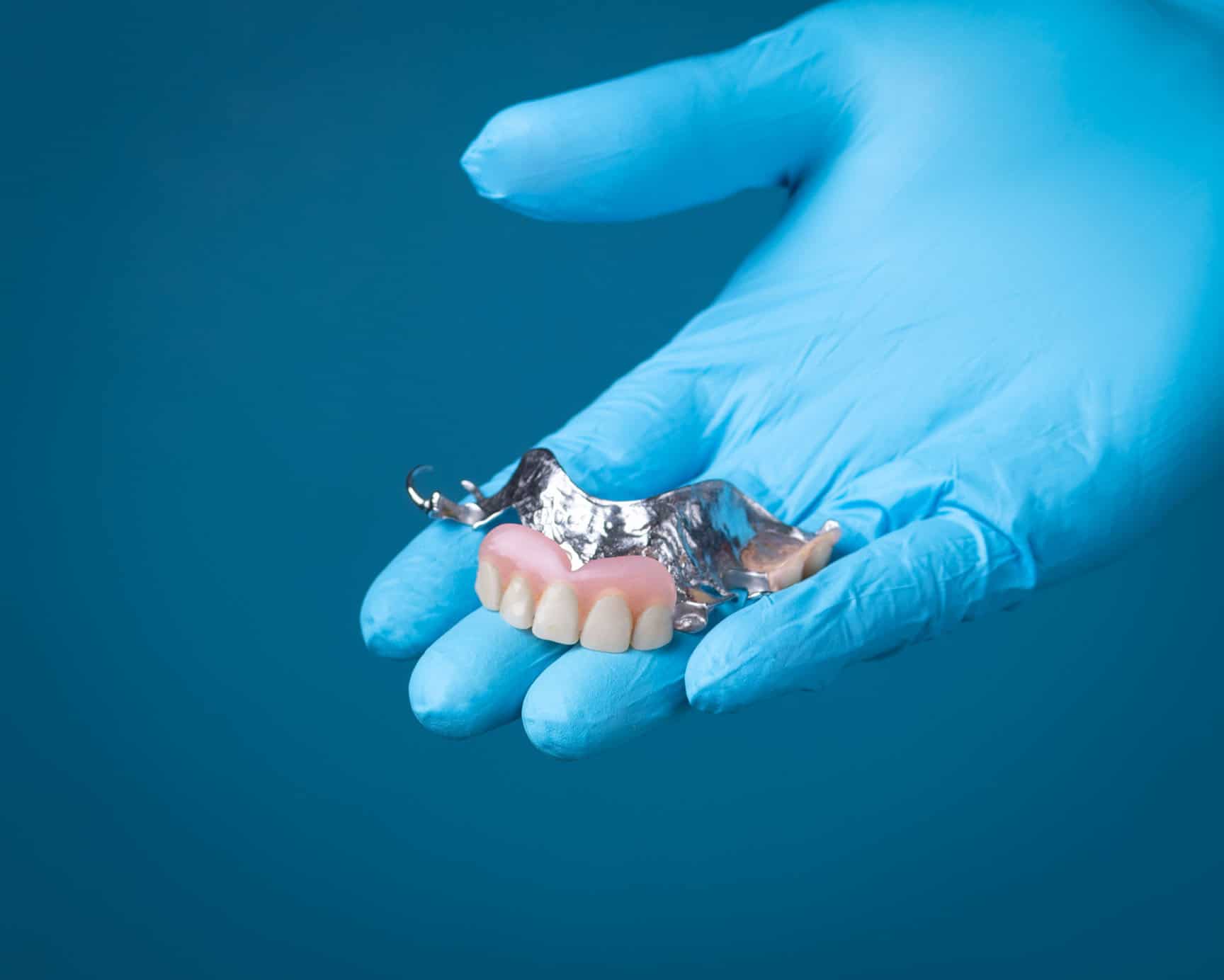 Partial denture held in gloved hand
